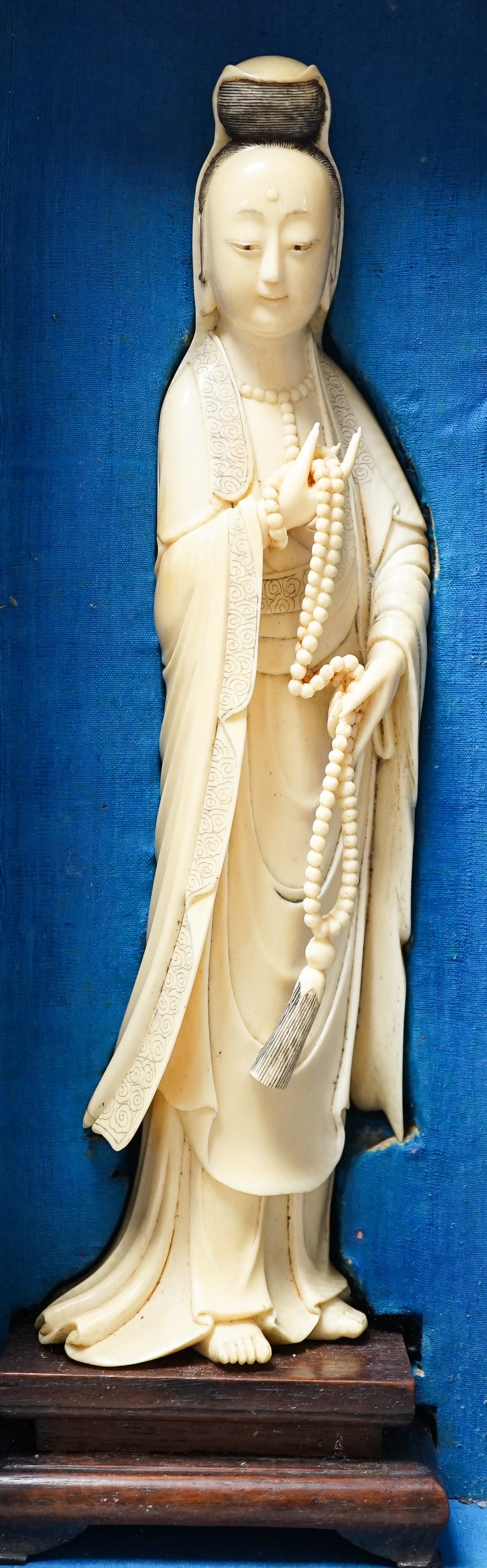 An early 20th century Chinese ivory figure of Guanyin holding a Buddhist rosary 25cm, wood stand and case
